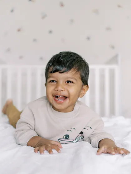 A little boy laughing on the bed. His happy, carefree spirit is perfectly captured in this shot.