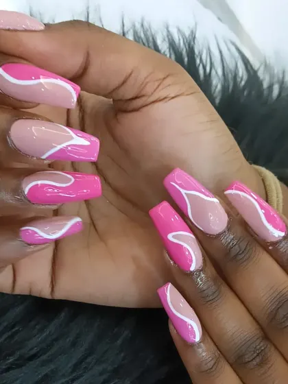 A playful pink abstract design with bold white and lighter pink swirls on long coffin nails.