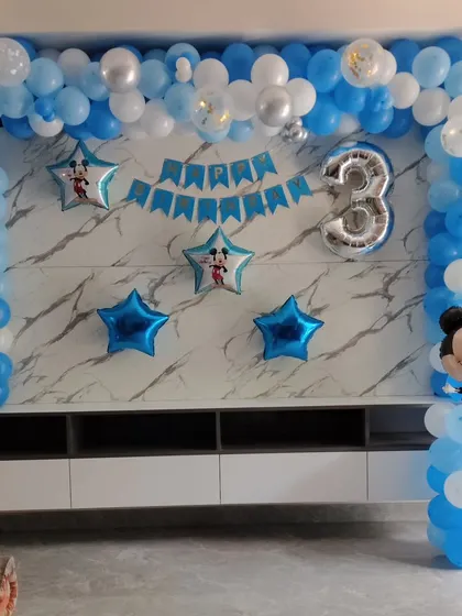A simple and sweet Mickey Mouse decoration for a 3rd birthday, set up against a home's TV unit. I used a blue and white balloon arch, star-shaped foil balloons, a '3' foil balloon, and a Mickey Mouse balloon character to create a festive corner.