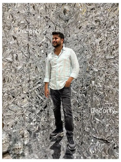 A guest posing in front of the crinkled silver foil backdrop, which provides a dynamic and high-fashion look for party photos.