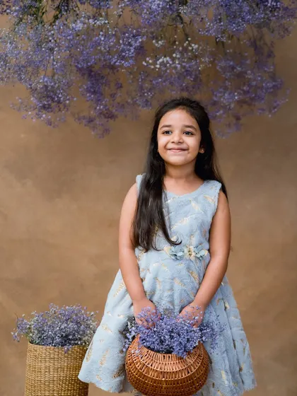 A beautiful fine art portrait with a basket of purple flowers against a simple brown backdrop.