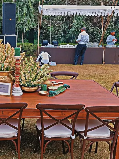 A rustic-chic dining setup for an outdoor event, with wooden tables and chairs and beautiful floral centerpieces.