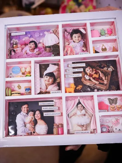 A full view of the baby girl's story frame, held by her parents, showcasing the intricate details in every compartment.