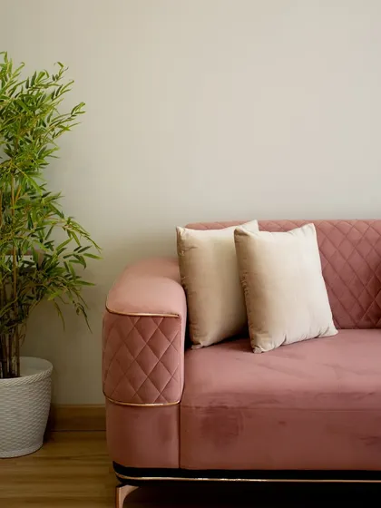 A close-up of the plush, rose-pink sofa with quilted details and metallic accents, adding a touch of luxury and comfort to the living room.
