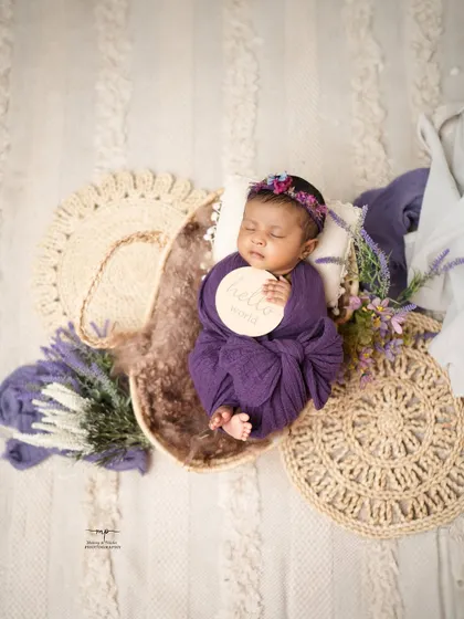 "Hello World!" This newborn is wrapped snugly in purple and placed in a moon-shaped prop, surrounded by soft lavender and boho textures.