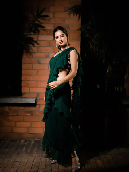 This full-length shot shows the beautiful flow of the emerald green ruffled saree gown. The layers of ruffles add movement and a contemporary feel to the classic saree drape.