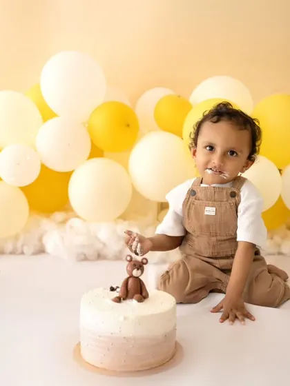 A proud smile from the birthday boy with his teddy bear cake. This yellow and white theme is perfect for a bright and happy first birthday shoot.