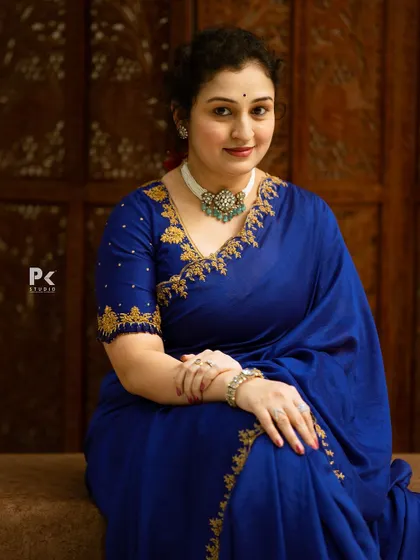 A seated portrait in the royal blue saree, showcasing the detailed craftsmanship of the embroidery.