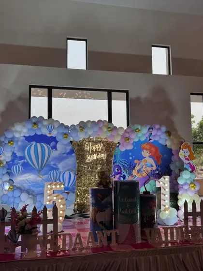 The full stage view of the hot air balloon and mermaid theme for twins. The setup includes two distinct backdrops, marquee numbers for each child's age, and themed plinths, all tied together with a cohesive color palette.