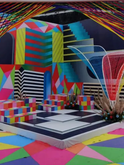 A vibrant and psychedelic carnival-themed brunch, featuring a stage with geometric patterns, bold colors, and string art installations for a fun and high-energy event.
