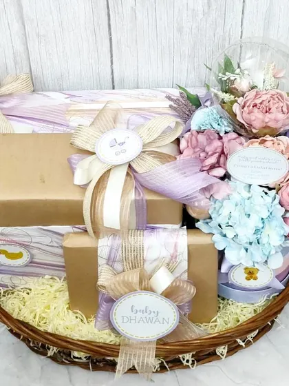 Another angle of the baby shower basket, showing the custom 'Baby Dhawan' tags and the careful arrangement of each gift. It's a joy to create gifts for such happy beginnings.