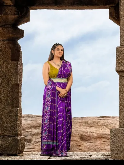A majestic shot at Hampi, where the purple silk saree and its drape stand out against the ancient ruins.