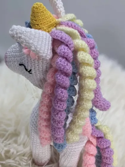 A side view of the pastel unicorn, showing off its beautiful, multi-colored curly tail.