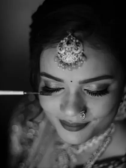 A close-up, black and white shot of the bride getting her makeup done. This intimate "getting ready" moment focuses on the details and anticipation before the main event.