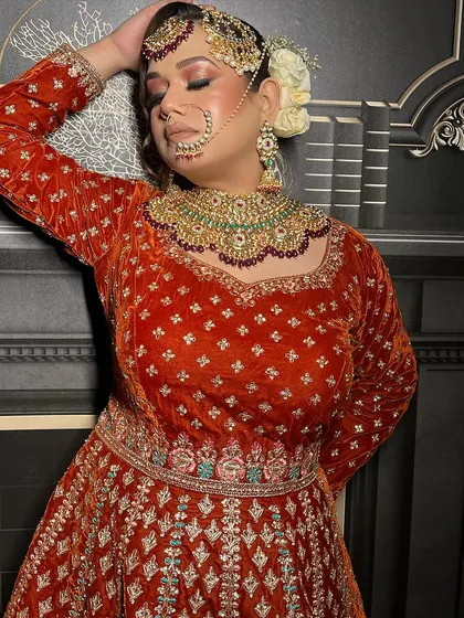 A close-up on the heavy bridal jewellery paired with a burnt orange velvet outfit.