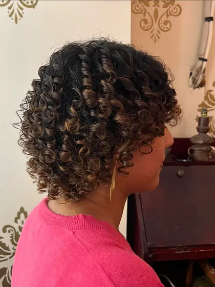 A side view showing the defined curl pattern and volume achieved with this curly bob haircut.