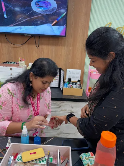 A trainer demonstrating the correct application of nail polish on a student.