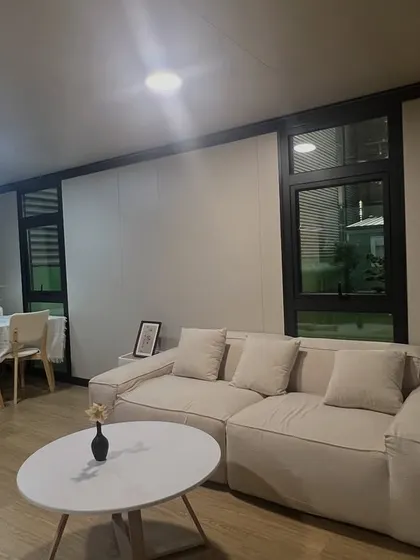 A well-lit living room in a modular home, featuring a comfortable sofa and a simple dining setup. My goal is to deliver a space that feels like home from day one.