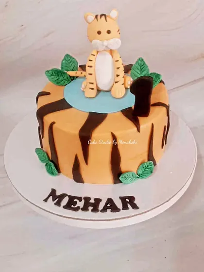 A cute tiger themed cake for a first birthday. The cake is decorated with tiger stripes and a sweet, hand-crafted tiger cub on top.
