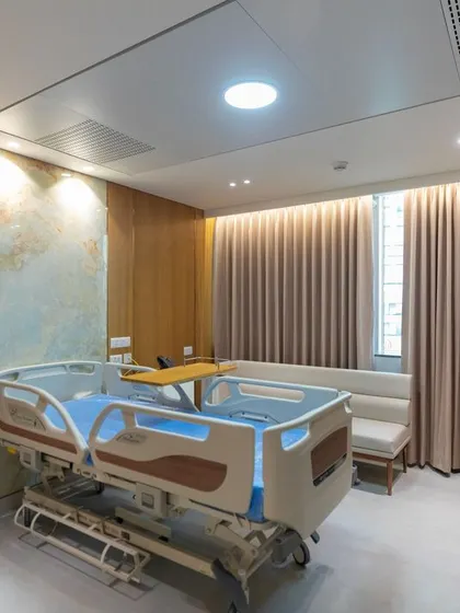 This patient room at Breach Candy Hospital is designed as a holistic healing environment. We used a warm color palette with a pop of yellow, soft curtains, and an art piece to create a tranquil space that promotes well-being.