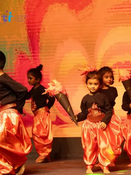 The "fire" dancers move across the stage, their orange costumes glowing under the stage lights.