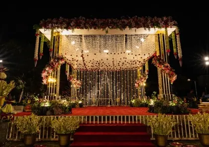 A beautifully lit mandap in Udaipur, ready for a nighttime ceremony. The combination of floral strings and a glittering backdrop creates a magical effect.