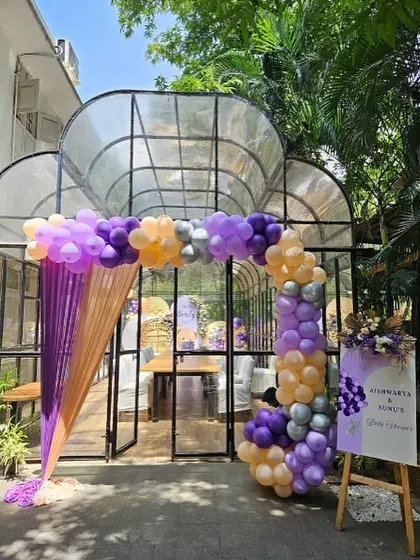 The entrance to the glasshouse venue, decorated with a beautiful balloon arch in purple, peach, and silver.