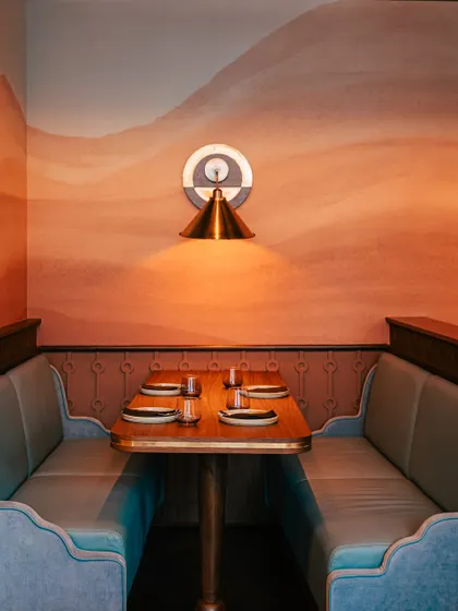 A private booth set against a mural of rolling hills, offering a perfect little escape. It’s an ideal spot for a quiet dinner or a long conversation.
