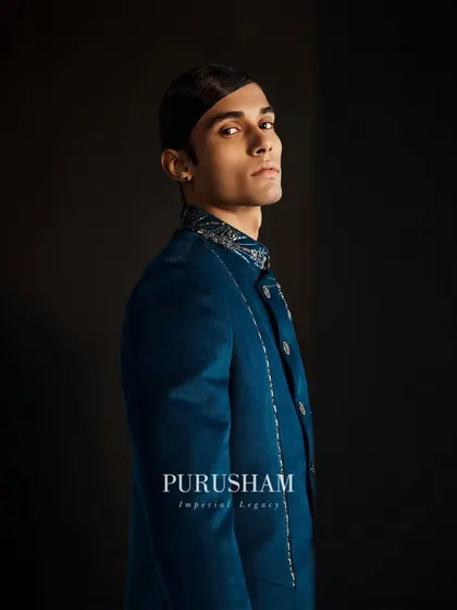 A profile view of the deep teal jacket. The intricate collar and shoulder embroidery add a touch of modern royalty to this striking piece.