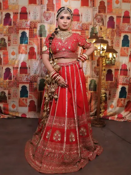 A full shot of a classic red bridal lehenga with vertical golden stripes and a heavily embroidered border. This design is great for creating a taller, more streamlined silhouette.