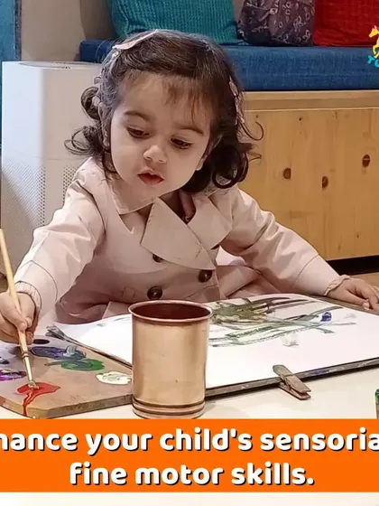 A toddler carefully dabs her paintbrush, a perfect example of our parent-toddler sessions. These activities are designed to enhance fine motor skills and sensory development.
