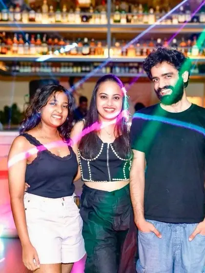 A group of friends smiling for the camera against the backdrop of the bar and party lights.