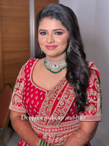 A full portrait of the bride in her red lehenga, showcasing the complete look with flawless makeup.