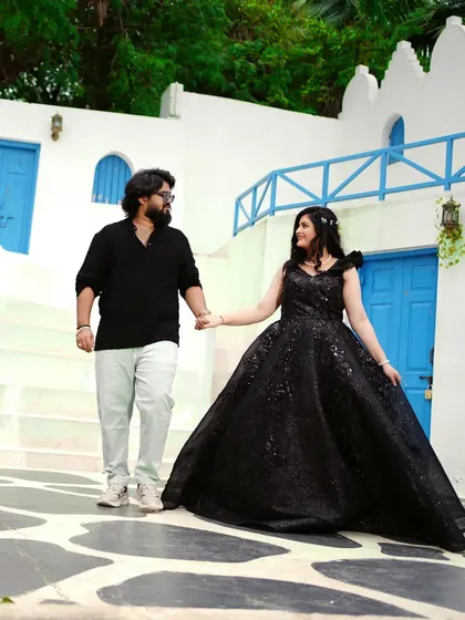 A pre-wedding shoot with a Santorini vibe. The bride-to-be is wearing a magnificent black sequin ballgown that creates a stunning silhouette against the white and blue architecture.