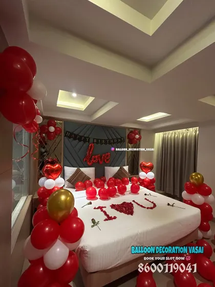 An angled view of a classic red and white romantic room surprise. This shows the balloon columns and how the decorations frame the bed, making it the focal point of the room.