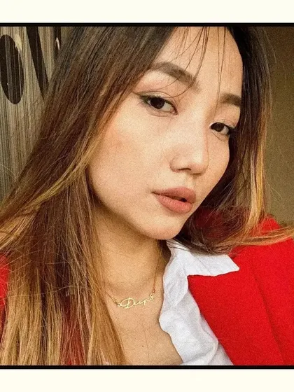 A customer photo showing our gold script name necklace. It's a great example of how this personalized piece looks as part of a stylish, everyday outfit.