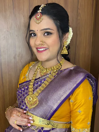 A close-up of Dharshini's baby shower look. The soft makeup and traditional gold jewelry perfectly complement her purple and yellow silk saree.
