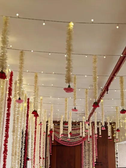 A wider view of the hanging floral decor, showing how the red and white strings can define a space and create a beautiful canopy over an entrance or seating area.