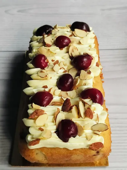 This is my Cherry Almond Tea Cake. It’s a moist almond cake with sweet cherry flavors, topped with almond buttercream, fresh cherries, and crunchy sliced almonds.
