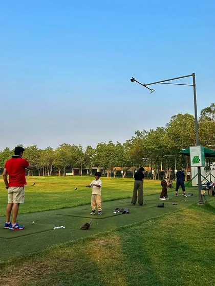 A father and son practice together on the driving range. Golf is a fantastic way for families to spend quality time outdoors.