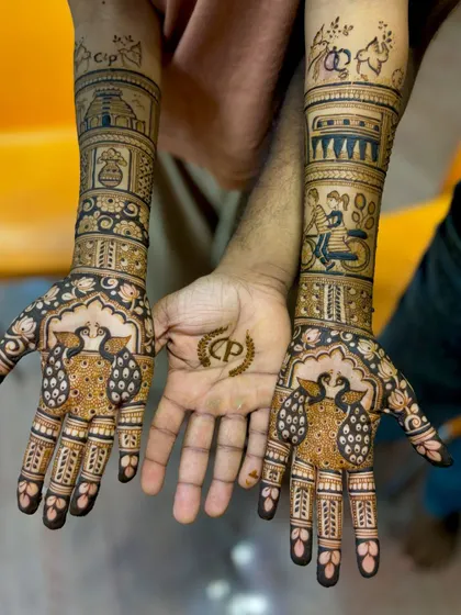 This unique engagement mehendi tells the couple's story, with illustrations of a temple, a train, and a bicycle ride, plus a matching initial design for the groom.