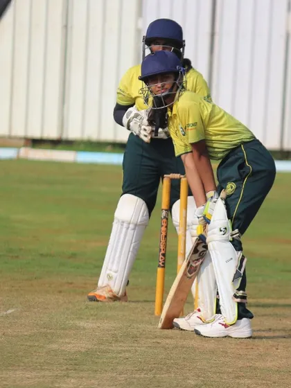 A batter and wicketkeeper ready for the next delivery, a classic scene from a competitive cricket match.