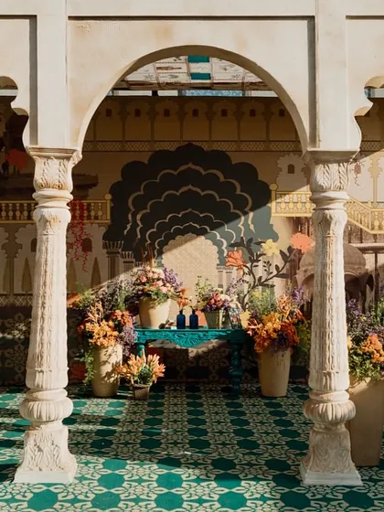 A view through the carved columns of the pavilion, looking towards a floral-adorned photo corner. The layers of architecture and decor create beautiful, frame-worthy vistas throughout the venue.
