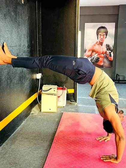 This student holds a wall-assisted backbend, with the iconic Bruce Lee poster in the background for inspiration.