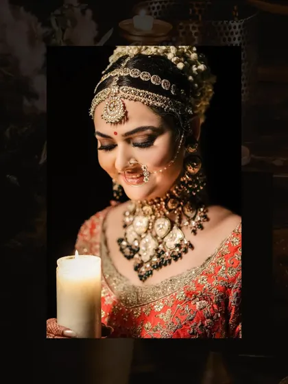 A close-up bridal portrait with a candle, creating a soft and intimate glow. The focus is on her serene expression and the intricate details of her jewelry and makeup.