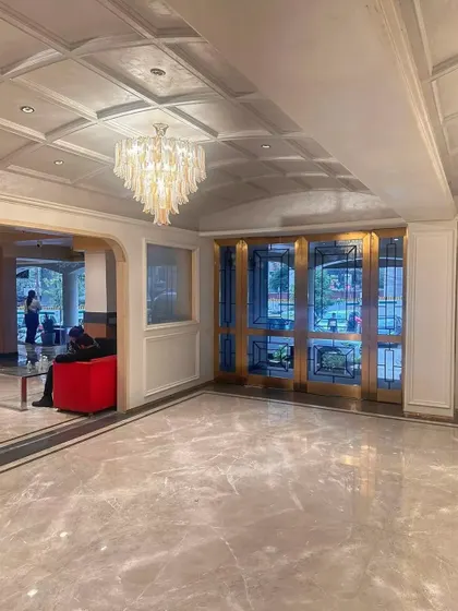 The main entrance doors of the Bhopal hotel, featuring intricate metalwork and flanked by marble-clad walls. This grand entrance sets a luxurious tone for the entire property.