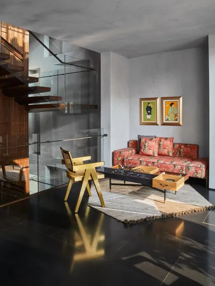 This seating area in the Baid Residence showcases our eclectic style. A floral sofa is paired with a modern brass chair by Mahendra Doshi and a coffee table by Mogg, all set against a backdrop of artwork by Lalu Prasad Shaw.