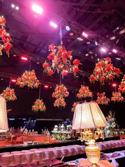 A view across the catering setup, where chandeliers dripping with red roses hang above, ensuring that the theme of opulence extended to every corner of the venue.