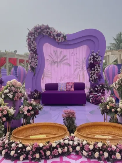 Pre-wedding functions should be just as beautiful as the main event. This whimsical purple-themed Mehendi setup features a custom-designed stage with floral hot-air balloon props and traditional brass urlis, creating a fun and picturesque environment.