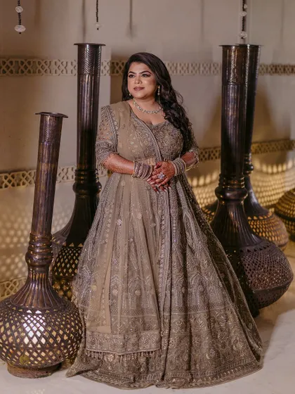 A stunning portrait of the bride posing with elegant floor vases. Her regal lehenga and confident pose create a majestic image.